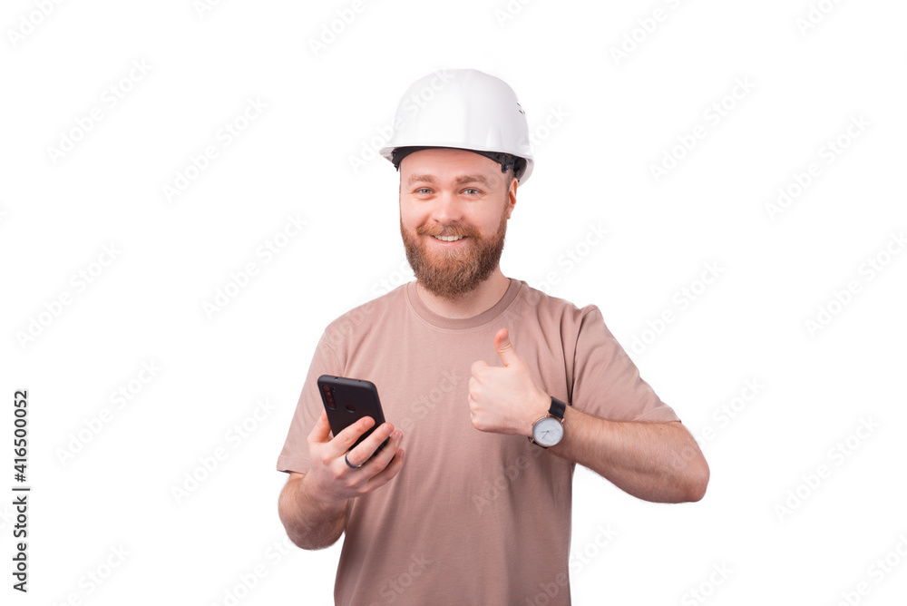 Smiling young architect man holding smartphone and showing thumb up gesture