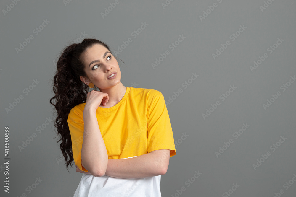 portrait of a young teenager with long wavy hair dressed in a yellow t-shirt, isolated on gray background portrait of a young teenager with long wavy hair dressed in a yellow t-shirt, isolated on gray background