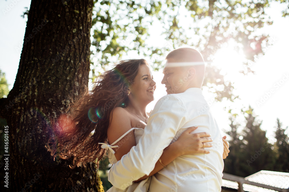 Fototapeta premium loving young couple having fun outdoors on summer sunny day. Man and woman are hugging near tree in park. valentines day