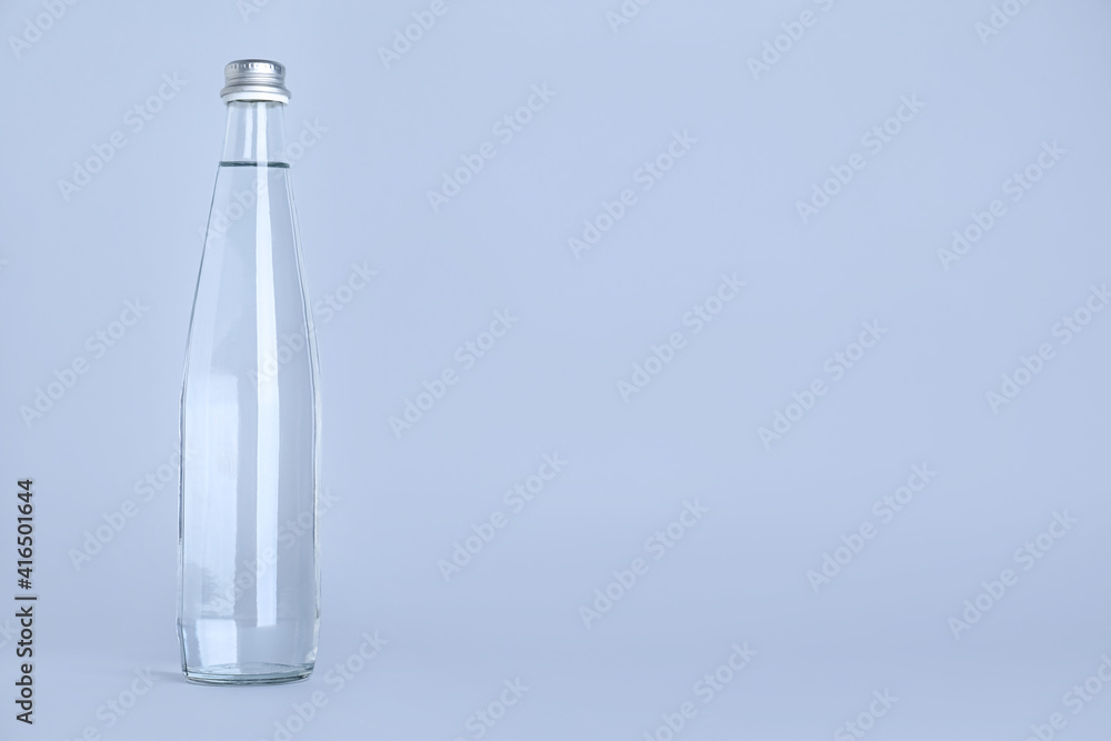 Glass bottle with water on light grey background, space for text Glass bottle with water on light grey background, space for text