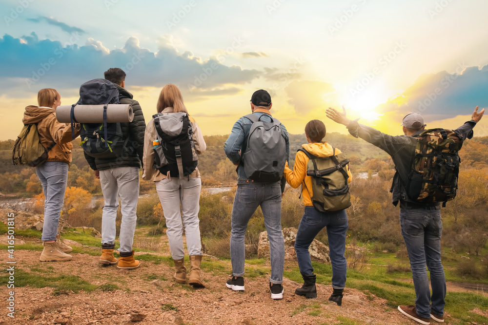 Group of hikers with backpacks in mountains, back view