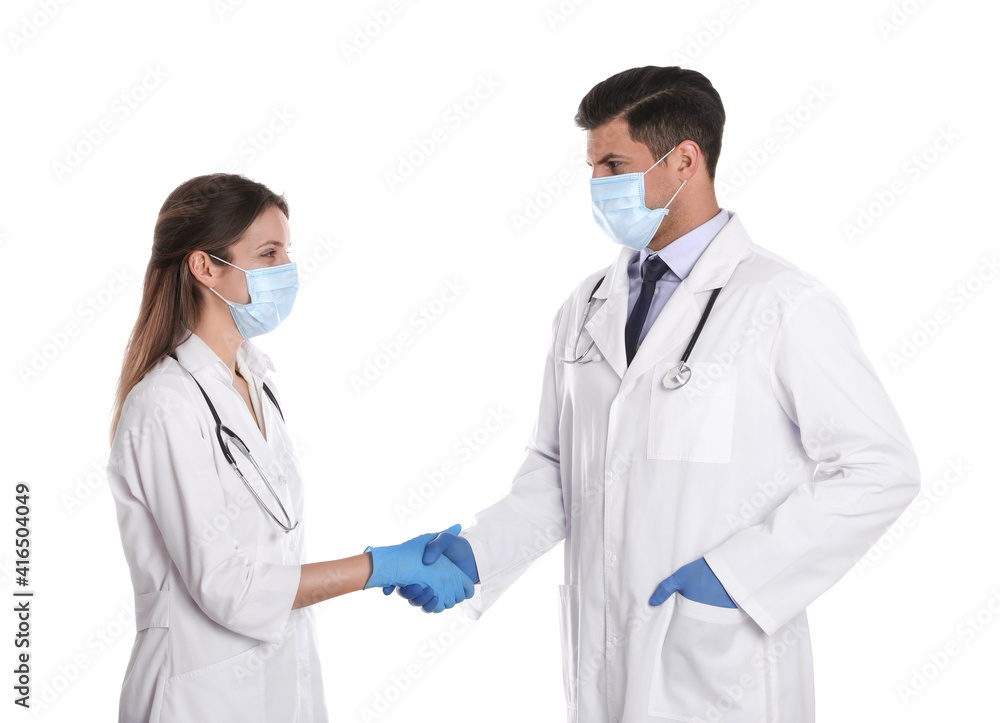 Doctors in medical face masks shaking hands on white background Doctors in medical face masks shaking hands on white background