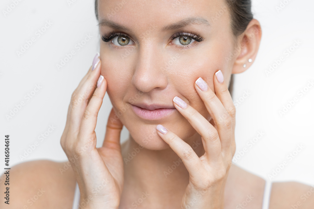 Close up of beautiful young woman with clean fresh skin and french manicure holding her cheeks. Natural beauty face care. Facial treatment. Cosmetology, beauty and spa