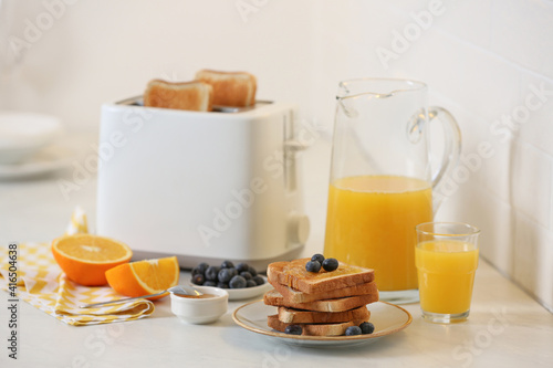 Modern toaster and tasty breakfast on white table in kitchen