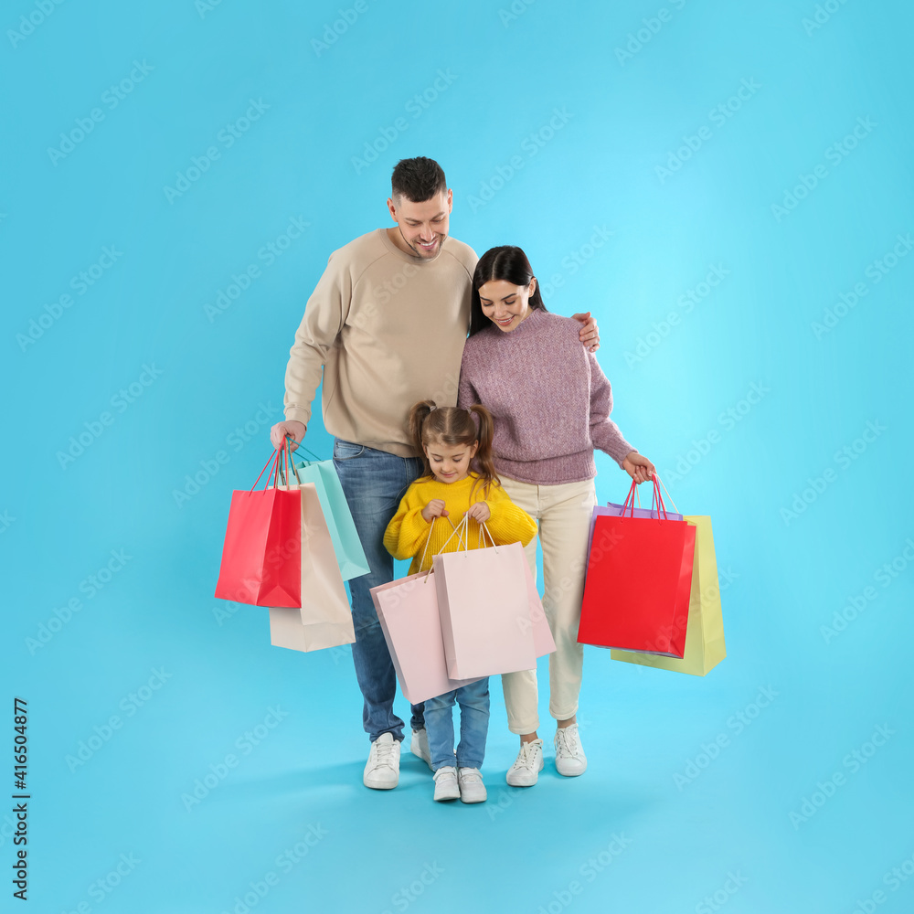 Happy family with paper bags on light blue background. Christmas shopping Happy family with paper bags on light blue background. Christmas shopping