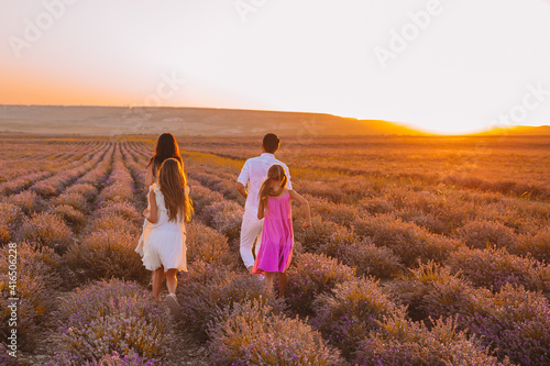 Family in lavender flowers field at sunset in white dress and hat