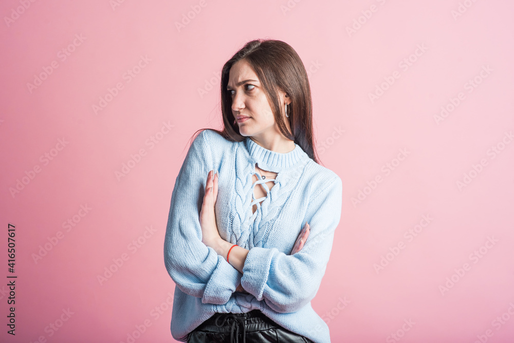 Angry emotions of a brunette girl in the studio on a pink background Angry emotions of a brunette girl in the studio on a pink background