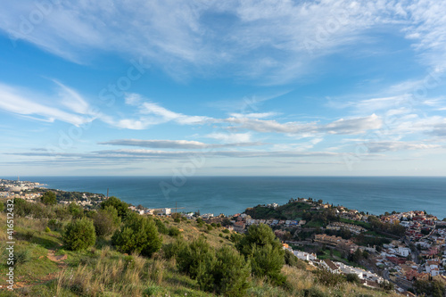 view of the city and the sea from the top of the hill with the cloudy sky in the background © victor