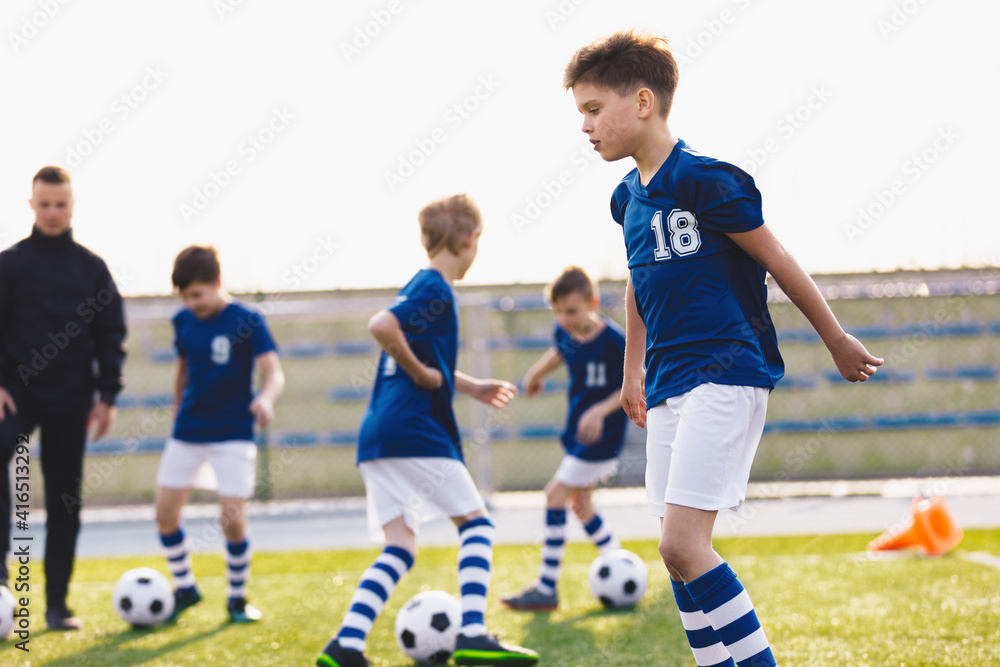 Obraz premium Football Education for Kids. Physical Education for Children. Young Coach With Kids in Soccer Team on Training Unit. Youth Team Coach Training School Boys in Football Soccer