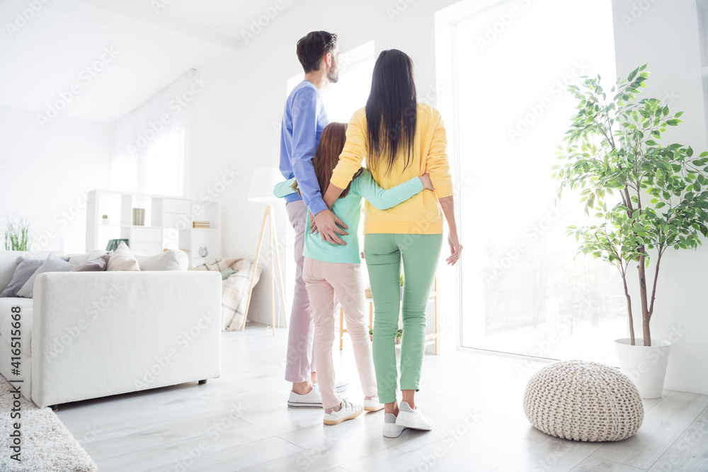 Full body rear view photo of family hug cuddle embrace look watch window enjoy time together indoors Full body rear view photo of family hug cuddle embrace look watch window enjoy time together indoors