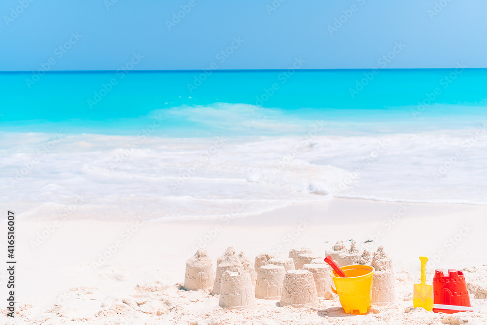 Sandcastle at white tropical beach with plastic kids toys Sandcastle at white tropical beach with plastic kids toys