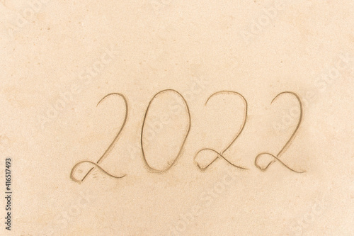 2022 Year message handwritten on the sand beach background. New Year concept.