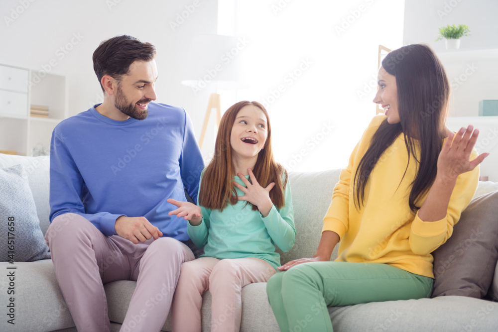 Photo of young cheerful family girl speak tell funny stories mom dad amazed surprised happy smile sit sofa home Photo of young cheerful family girl speak tell funny stories mom dad amazed surprised happy smile sit sofa home