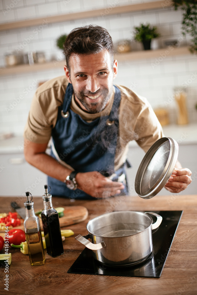 Handsome man preparing pasta in the kitchen. Guy cooking a tasty meal. Handsome man preparing pasta in the kitchen. Guy cooking a tasty meal.