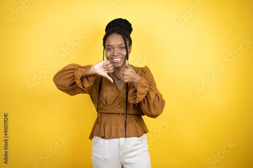 African american woman wearing casual clothes Doing thumbs up and down, disagreement and agreement expression. Crazy conflict