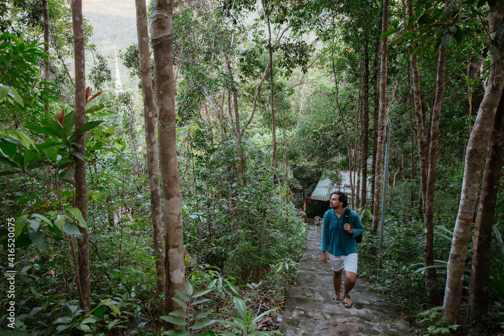 Male tourist climbs up the mountain in the tropical forest. Male tourist climbs up the mountain in the tropical forest.
