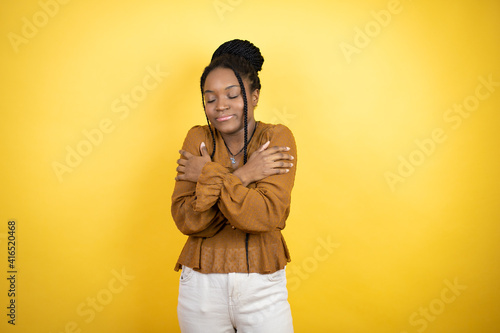 African american woman wearing casual clothes hugging oneself happy and positive, smiling confident © Irene