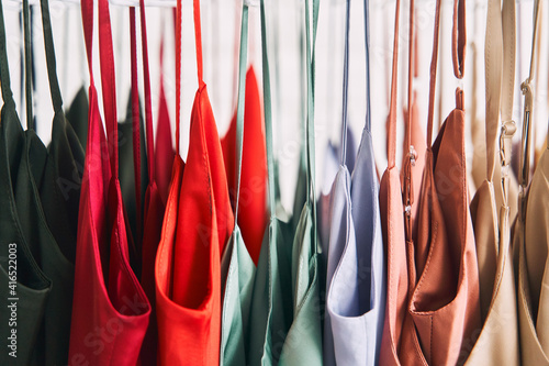 Multi-colored dresses hang on hangers in the store. Sale of women's dresses © Dima Anikin