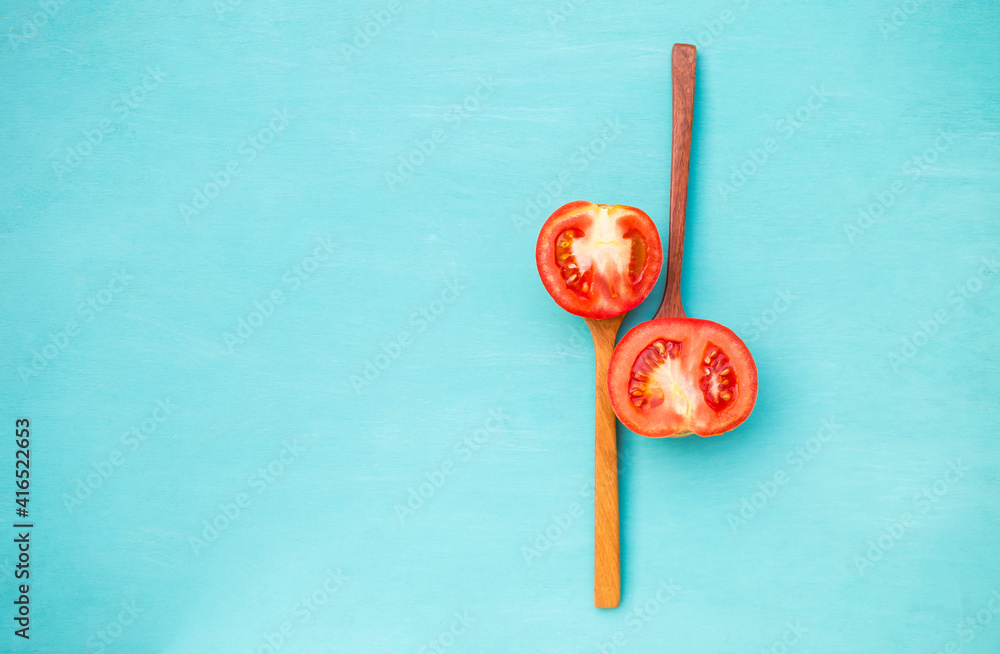 Fresh tomato slice on wooden spoon with space on blue background, healthy food style Fresh tomato slice on wooden spoon with space on blue background, healthy food style
