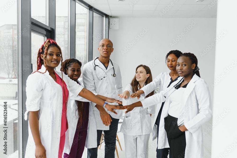Group of doctors putting hands together in clinic. Unity concept Group of doctors putting hands together in clinic. Unity concept