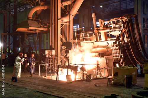 Fototapeta Naklejka Na Ścianę i Meble -  Workers in protective equipment in a foundry during the production of steel components - workplace industrial factory