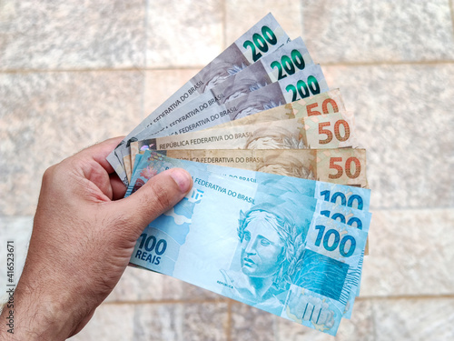 Real currency, money from Brazil. Brasil, Dinheiro, Reais, Hand. People holding in hand a brazilian banknotes.
