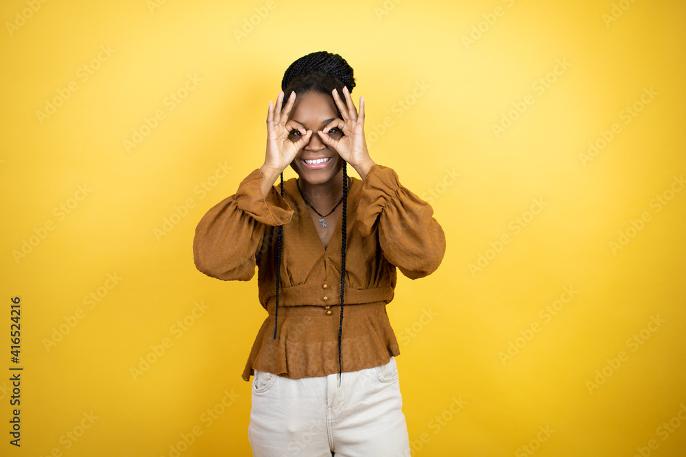 African american woman wearing casual clothes doing ok gesture shocked with smiling face, eye looking through fingers African american woman wearing casual clothes doing ok gesture shocked with smiling face, eye looking through fingers