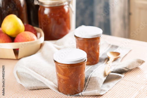 Homemade apple jam marmalade with cloves and cinnamon from organic apples in a transparent glass near wooden spoon. Homemade autumn jam confiture preserves.