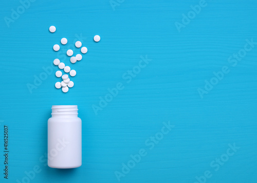 Pills, tablets and bottle on blue background.