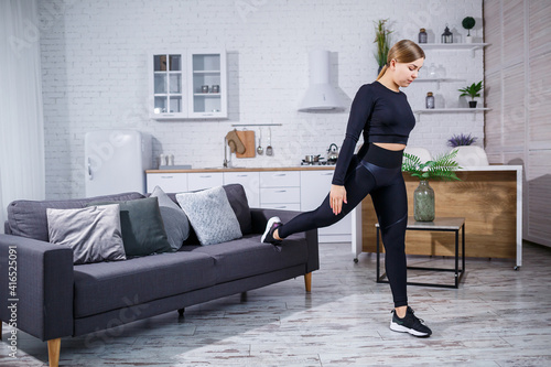Young beautiful sports girl in leggings and a top does exercises at home on the couch. Healthy lifestyle. The woman goes in for sports at home.