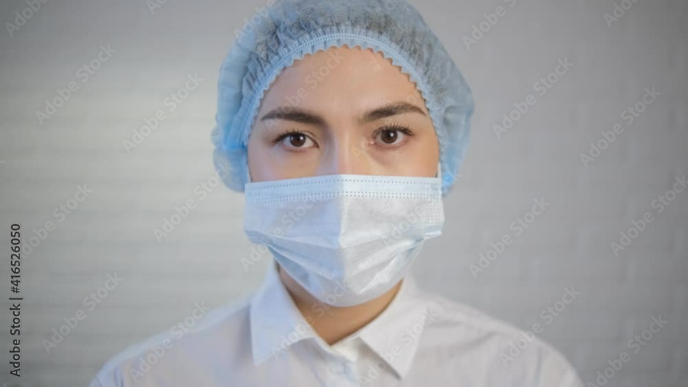 A female doctor during the coronavirus pandemic. Looks straight ahead. A close-up portrait of a tired doctor. Light blurred background A female doctor during the coronavirus pandemic. Looks straight ahead. A close-up portrait of a tired doctor. Light blurred background