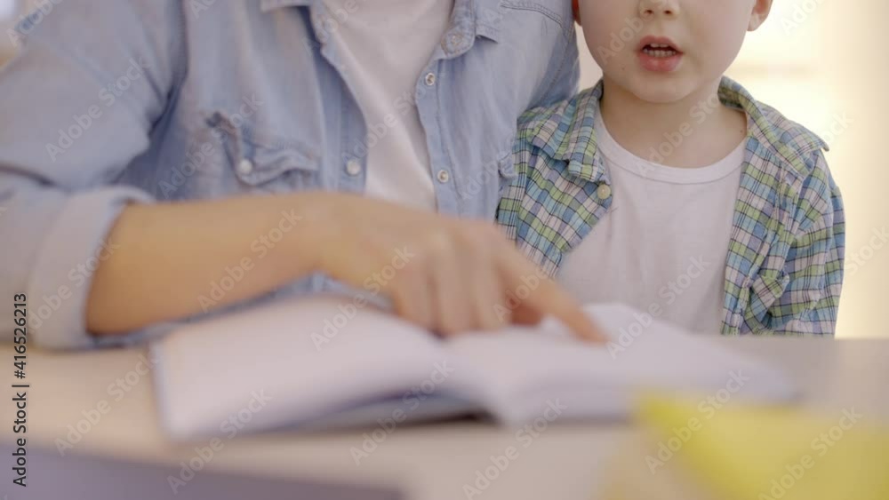 Mother encouraging son to read book, motivation of learning, child's development Mother encouraging son to read book, motivation of learning, child's development
