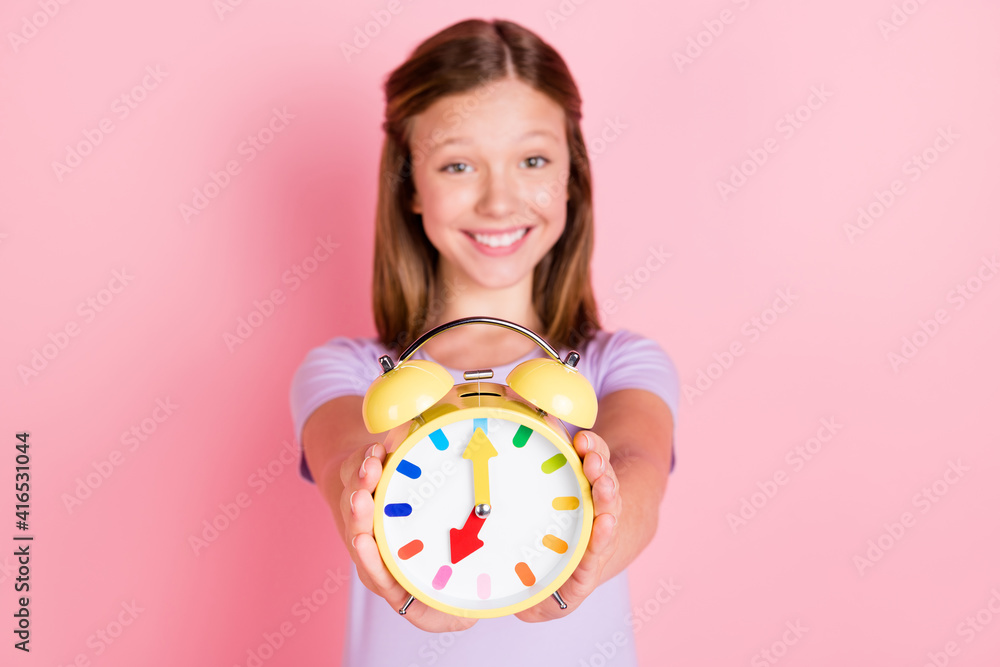 Photo of cheerful cute small girl hold alarm clock show you time isolated on pastel pink color background Photo of cheerful cute small girl hold alarm clock show you time isolated on pastel pink color background