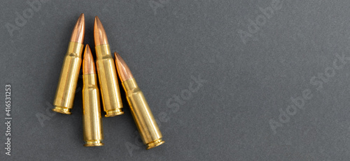 Four bullets on gray paper background. Cartridges 7.62 caliber for Kalashnikov assault rifle, closeup banner with copy space