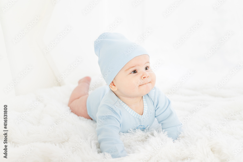 a baby in blue clothes is lying on his stomach on a white rug a baby in blue clothes is lying on his stomach on a white rug