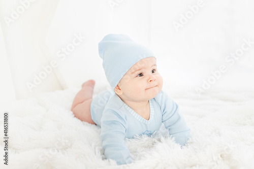 a baby in blue clothes is lying on his stomach on a white rug