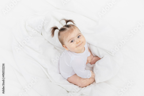 baby on the bed at home looking up, the concept of a happy loving family and children