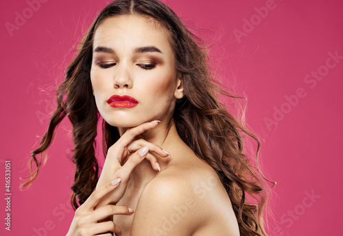 Woman on pink background with bright makeup red lips of brunette