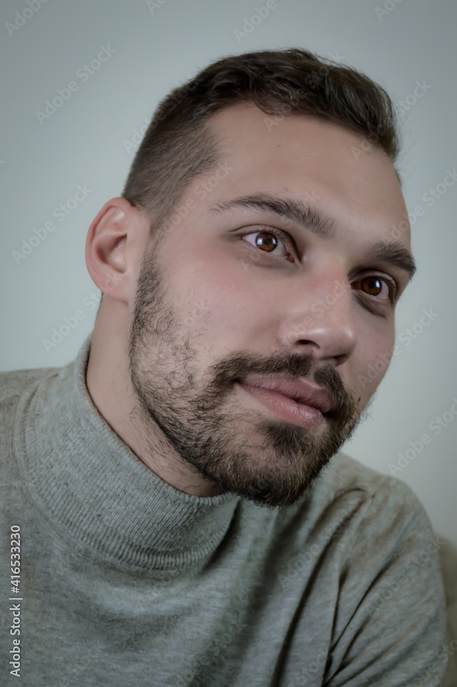 Portrait of a young brown-haired man with a short beard and a gray turtleneck sweater Portrait of a young brown-haired man with a short beard and a gray turtleneck sweater