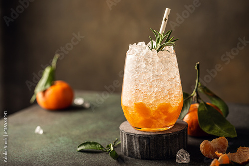 Fresh cocktail with crushed ice, rosemary and tangerines on the green table. Summer cold drink concept with copy space