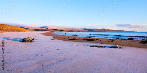 Brora beach in the Highlands in winter with snow on the sand and on the hills