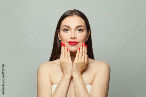 Cute young woman showing red manicured nails on hands. Body care and manicure concept