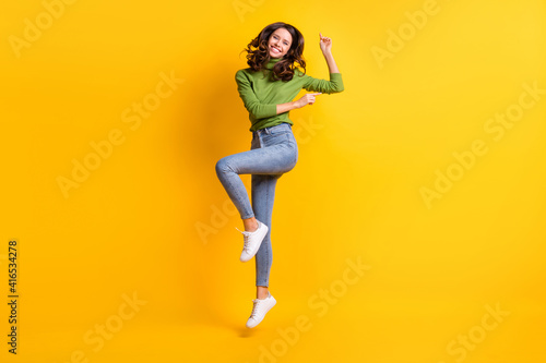 Full length photo of attractive happy joyful woman wear jeans jump up dance enjoy isolated on yellow color background