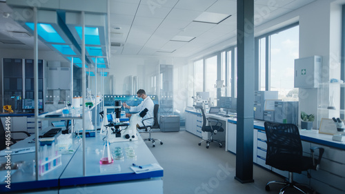 Modern Medical Research Laboratory: Caucasian Male Scientist Wearing Face Mask Working with Pipette, Analysing Biotechnology Sample. Advanced Scientific Lab for Drugs, Microbiology Development