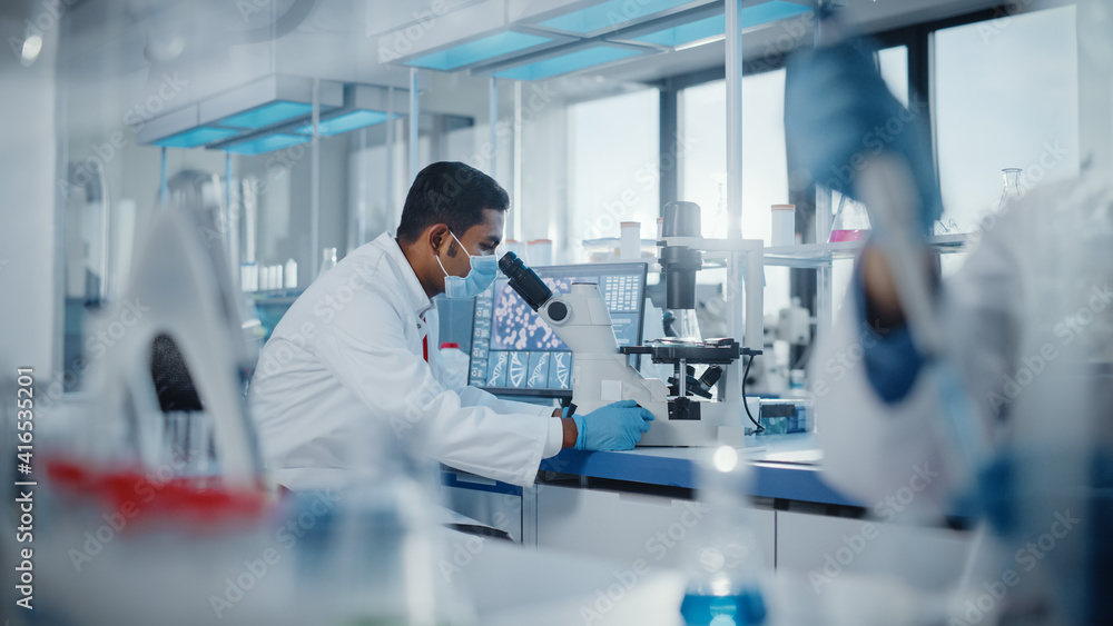 Medical Research Laboratory: Male Scientist Looking Under Micrsocope, Analyzing Samples. Advanced Scientific Lab Biotechnology, Medicine Development Medical Research Laboratory: Male Scientist Looking Under Micrsocope, Analyzing Samples. Advanced Scientific Lab Biotechnology, Medicine Development