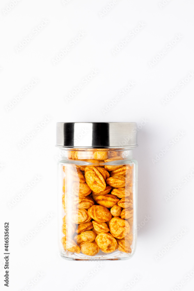 Roasted Crunchy Peanuts in a glass jar with a closed lid, made with peanuts. Indian spicy snacks (Namkeen), Top view, over the white background. Roasted Crunchy Peanuts in a glass jar with a closed lid, made with peanuts. Indian spicy snacks (Namkeen), Top view, over the white background.