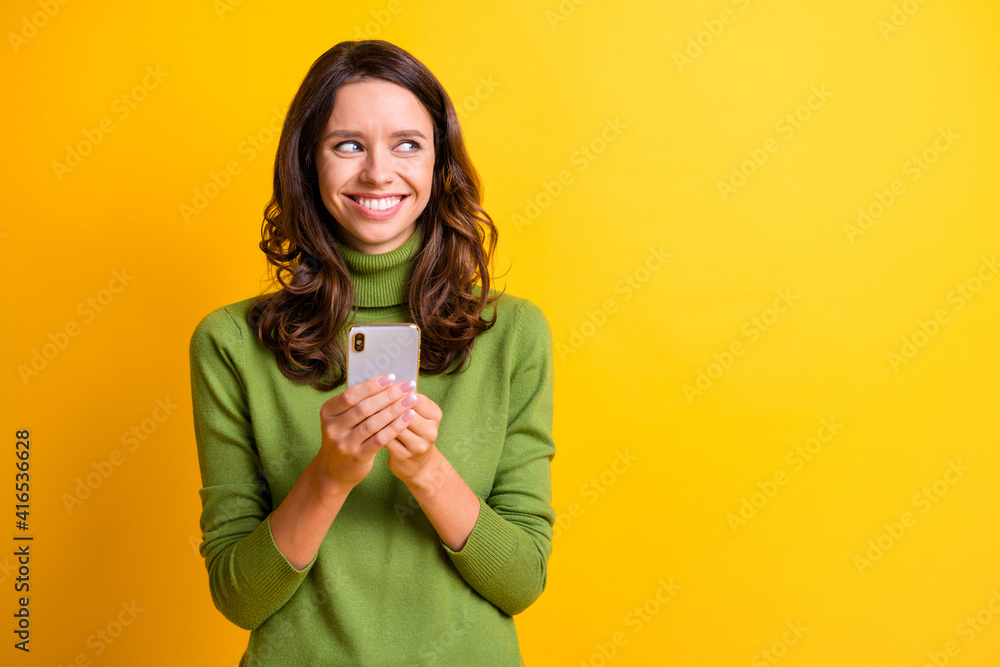 Portrait of young happy smiling cheerful woman look copyspace hold cellphone isolated on yellow color background Portrait of young happy smiling cheerful woman look copyspace hold cellphone isolated on yellow color background