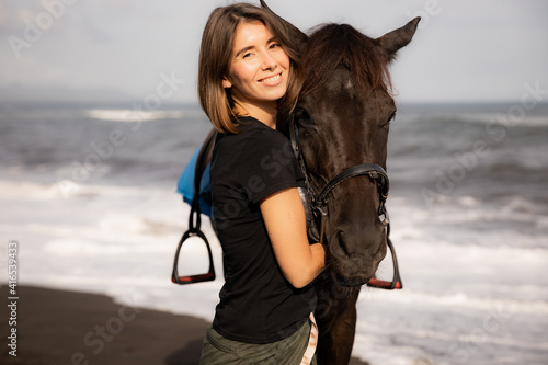 Portrait of happy woman and brown horse. Young Caucasian woman hugging horse. Romantic concept. Love to animals. Nature concept. Bali