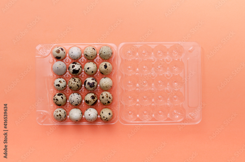 Top view of opened plastic package of quail eggs on the orange surface Top view of opened plastic package of quail eggs on the orange surface