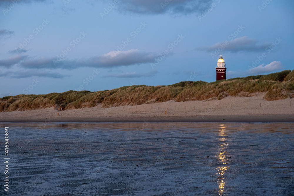 Lighthouse standing on the Dutch coast with a dramatic. and colorful dusk or dawn sky behind it. High quality photo